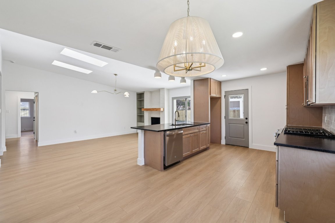10424 Quail Ridge Drive Austin, TX 78758 - Photo 36 of 37 Kitchen featuring a chandelier, open floor plan, a skylight, light wood-style floors, and recessed lighting