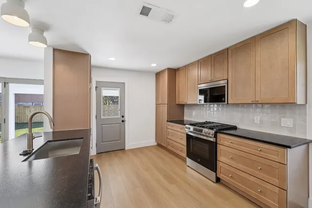 a kitchen with stainless steel appliances granite countertop a sink stove and cabinets