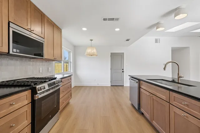 a kitchen with granite countertop wooden cabinets stainless steel appliances and a counter space
