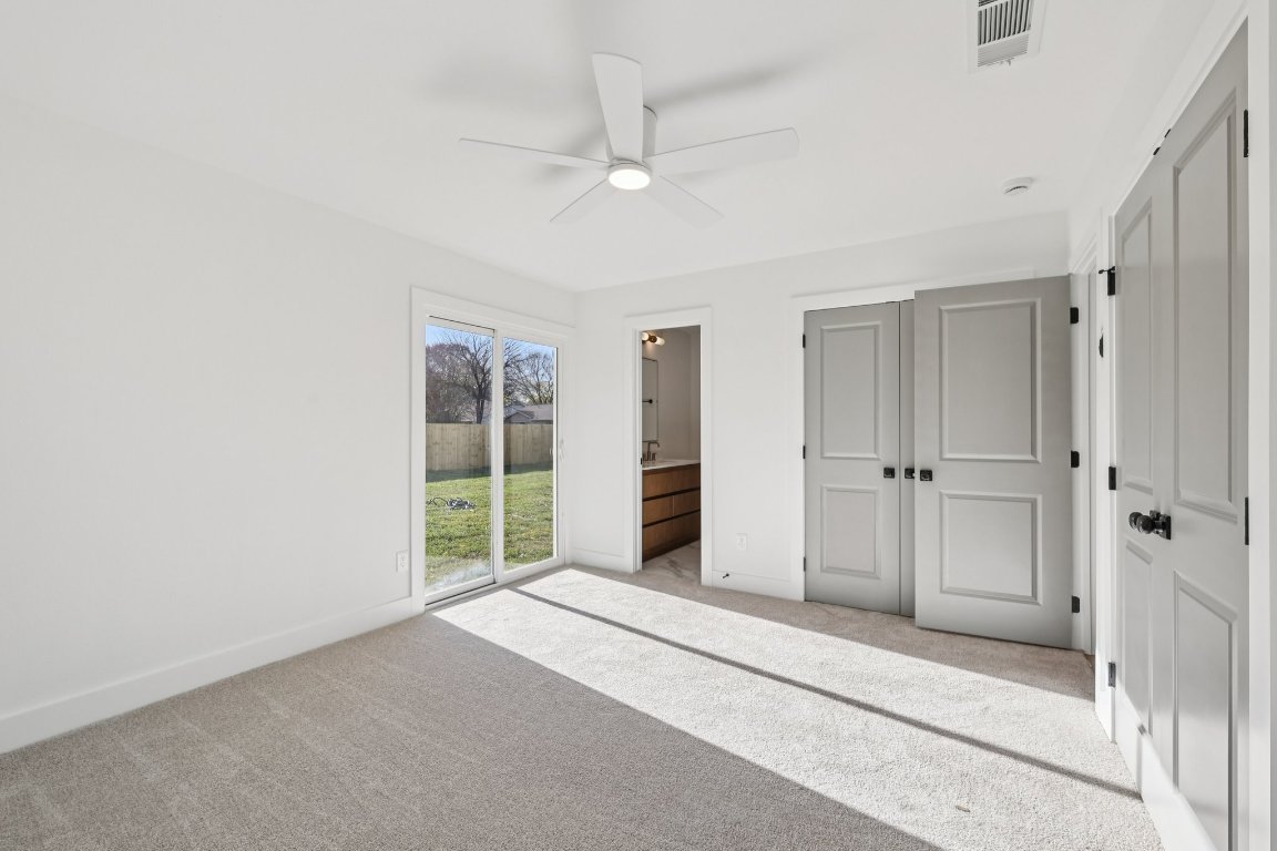 10424 Quail Ridge Drive Austin, TX 78758 - Photo 15 of 37 Unfurnished bedroom with carpet flooring, ceiling fan, a closet, ensuite bathroom, and access to outside