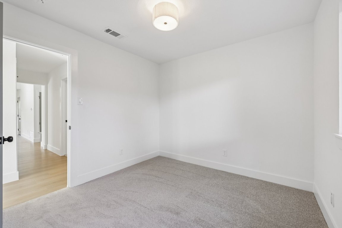 10424 Quail Ridge Drive Austin, TX 78758 - Photo 22 of 37 Empty room featuring light carpet and baseboards