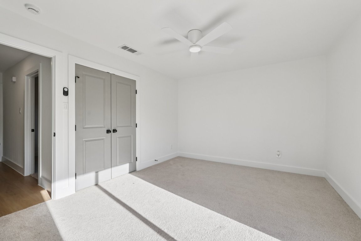 10424 Quail Ridge Drive Austin, TX 78758 - Photo 23 of 37 Unfurnished bedroom featuring a closet, light colored carpet, and a ceiling fan