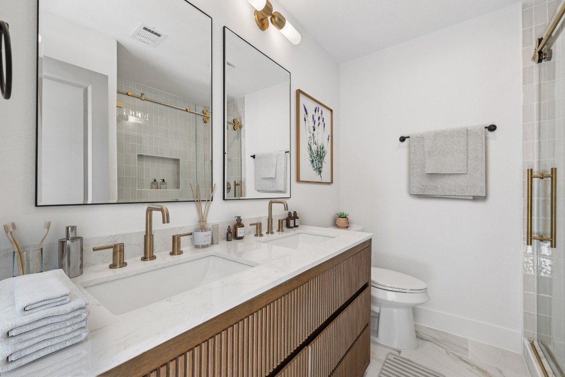 10424 Quail Ridge Drive Austin, TX 78758 - Photo 5 of 37 Bathroom featuring double vanity, a stall shower, and light marble finish flooring