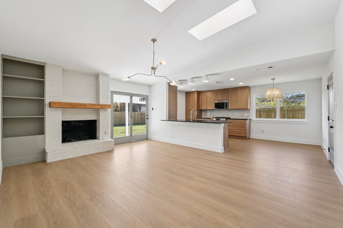 10424 Quail Ridge Drive Austin, TX 78758 - Photo 35 of 37 Kitchen with open floor plan, brown cabinets, a chandelier, decorative light fixtures, and vaulted ceiling