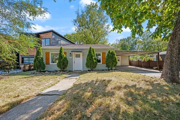 a view of a house with a yard and large tree