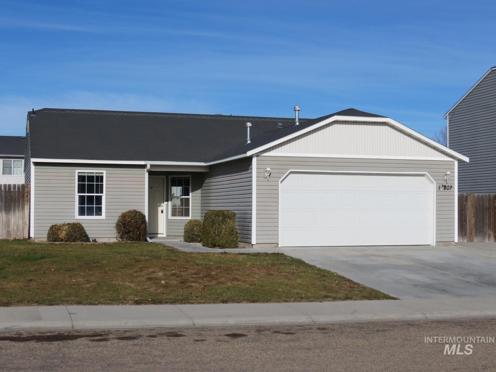Ranch-style home featuring a garage, driveway, and roof with shingles