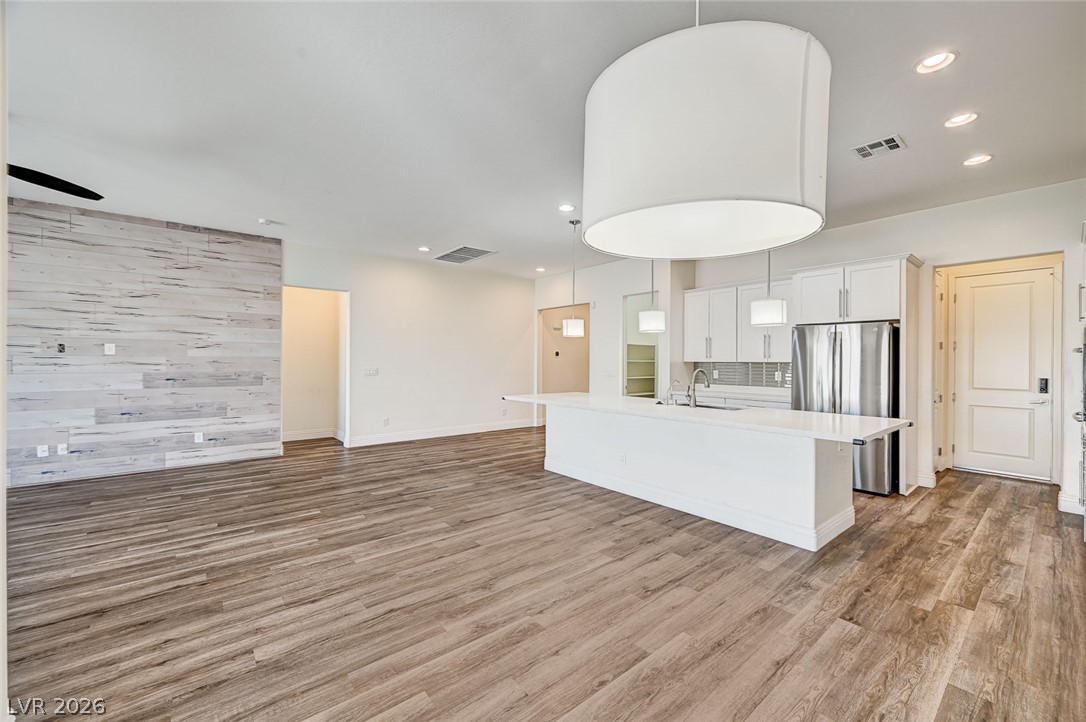 8197 Riley Love Street Las Vegas, NV 89139 - Photo 46 of 48 An open floorplan seamlessly connects the well-lit kitchen with a spacious living area, featuring rich hardwood flooring.