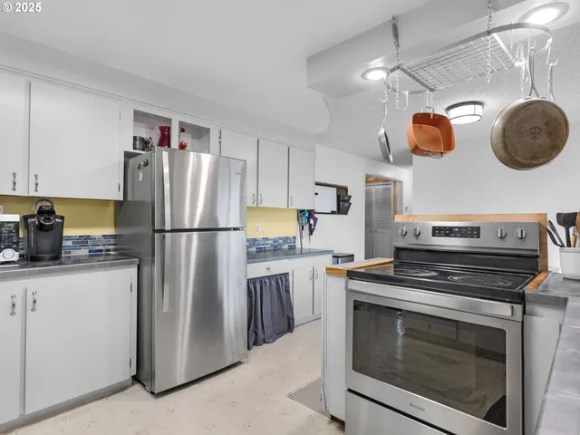 a kitchen with stainless steel appliances granite countertop a refrigerator a stove and a sink