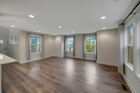a view of an empty room with window and wooden floor