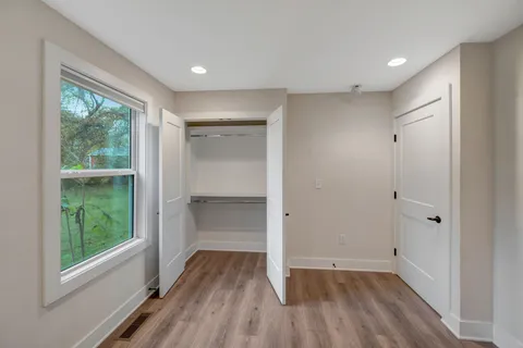 a view of empty room with wooden floor and fan