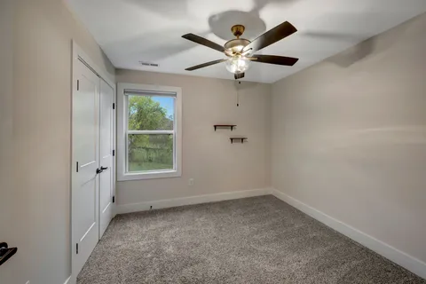 an empty room with a window and a fan
