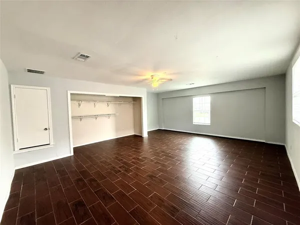 an empty room with wooden floor and windows