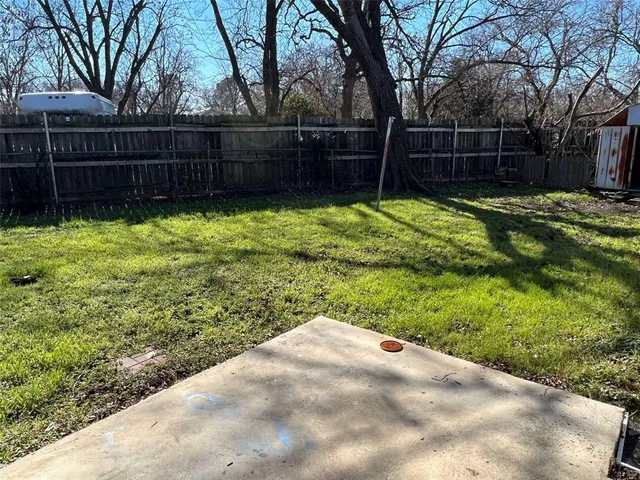 a view of backyard with wooden fence and trees