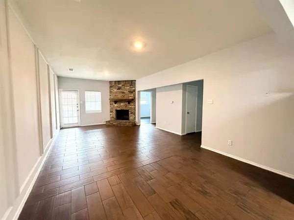 a view of empty room with wooden floor and fireplace