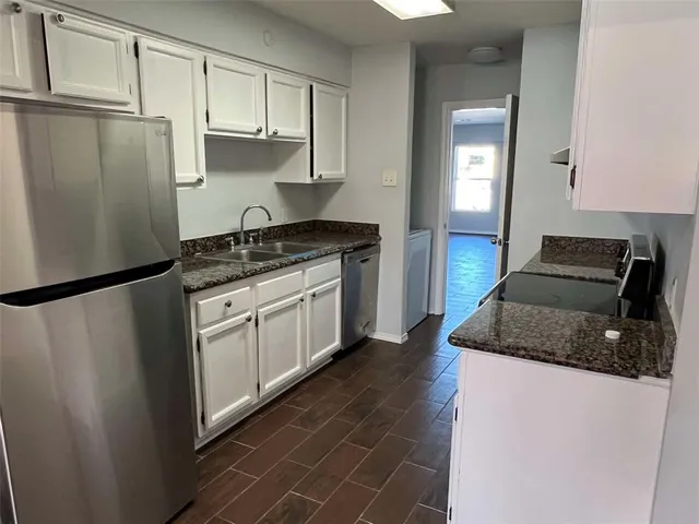 a kitchen with stainless steel appliances granite countertop a refrigerator a stove a sink and white cabinets