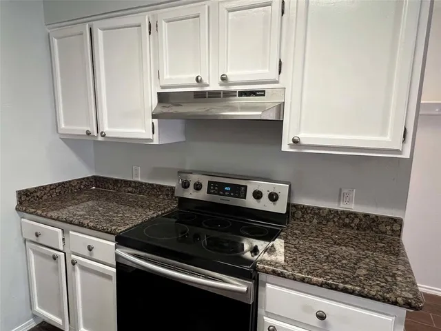 a kitchen with granite countertop a stove and a white cabinet