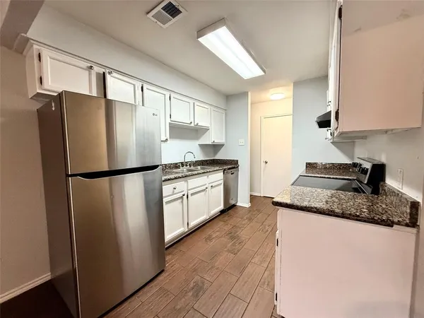 a kitchen with stainless steel appliances granite countertop a refrigerator a sink a stove and white cabinets