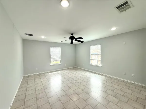 an empty room with windows and ceiling fan