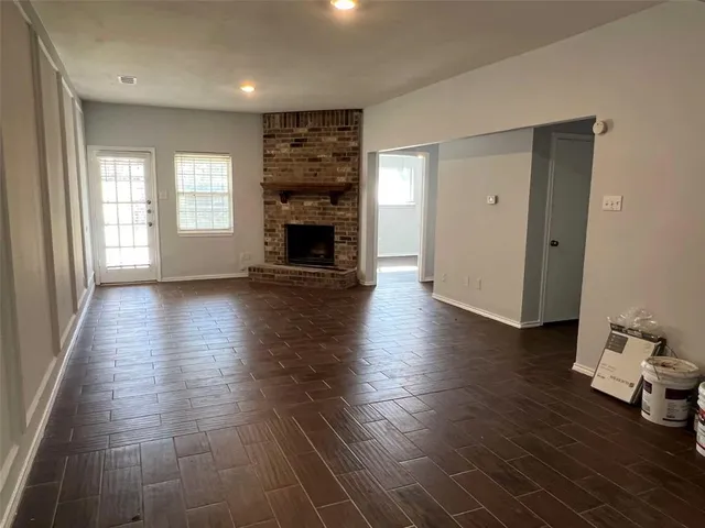 an empty room with wooden floor and a fireplace
