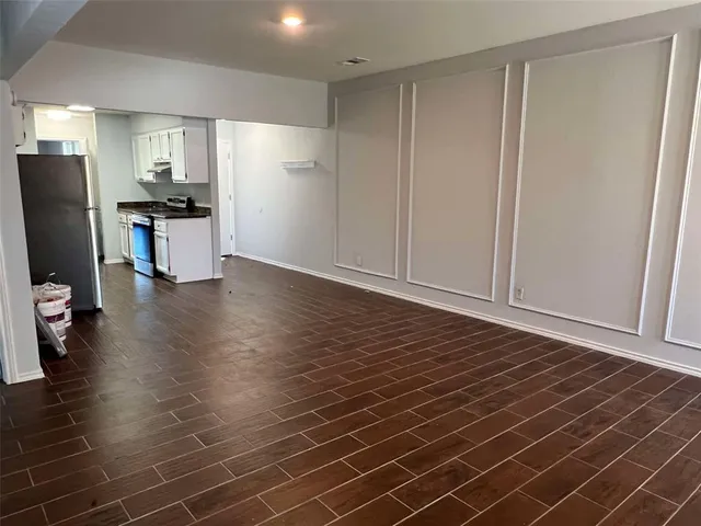a view of a kitchen with refrigerator and wooden floor