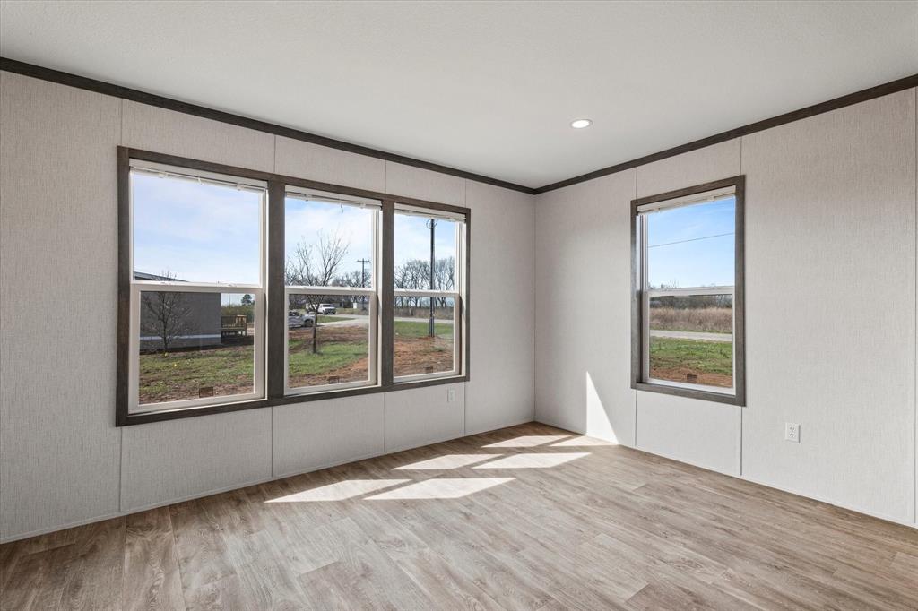 3888 Sandusky Road Whitesboro, TX 76273 - Photo 15 of 39 Unfurnished room with crown molding, a healthy amount of sunlight, and wood finished floors