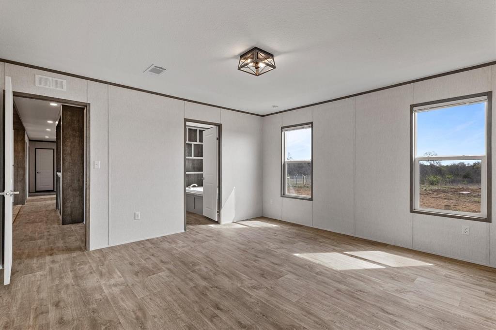 3888 Sandusky Road Whitesboro, TX 76273 - Photo 19 of 39 Unfurnished bedroom featuring connected bathroom, visible vents, crown molding, and wood finished floors