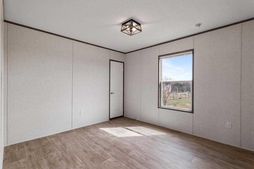 3888 Sandusky Road Whitesboro, TX 76273 - Photo 26 of 39 Empty room with ornamental molding and wood finished floors