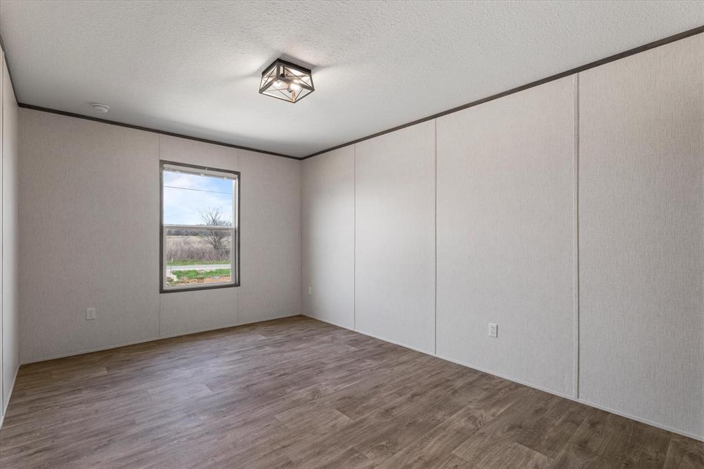 3888 Sandusky Road Whitesboro, TX 76273 - Photo 28 of 39 Empty room with wood finished floors, ornamental molding, and a textured ceiling