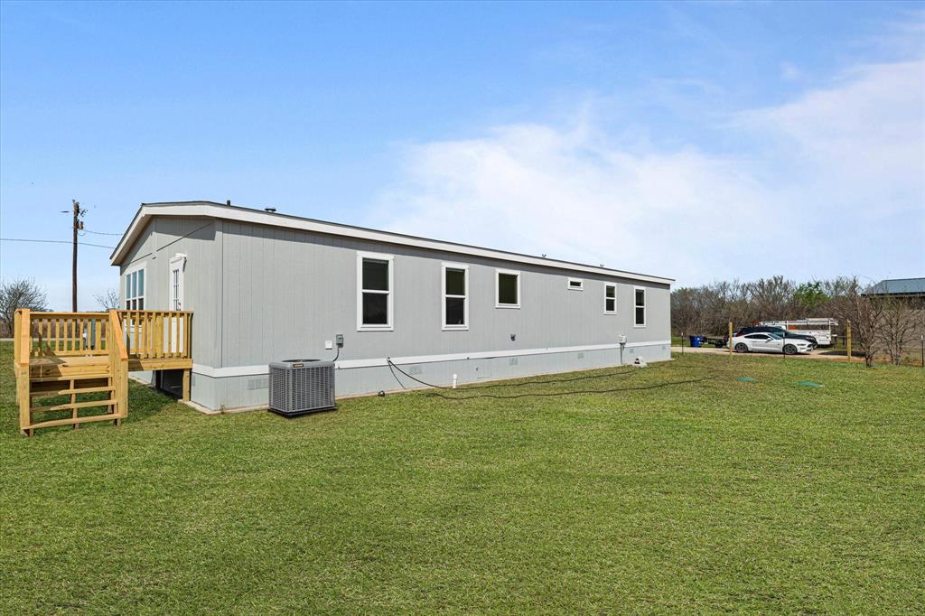 3888 Sandusky Road Whitesboro, TX 76273 - Photo 38 of 39 Back of house with central AC unit, a deck, and a lawn
