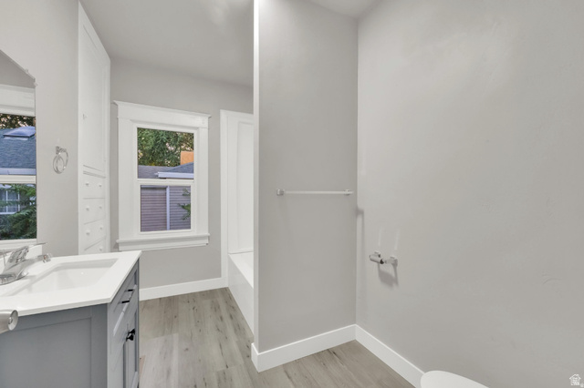 197 West Center Street Midvale, UT 84047 - Photo 10 of 12 Full bath featuring vanity, light wood-style flooring, a tub, and a shower