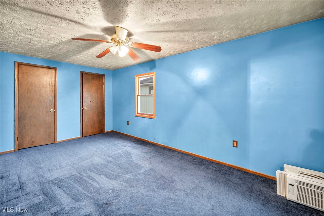 9982 Crow Road Litchfield, OH 44253 - Photo 36 of 41 Unfurnished bedroom featuring carpet flooring, ceiling fan, a textured ceiling, and multiple closets