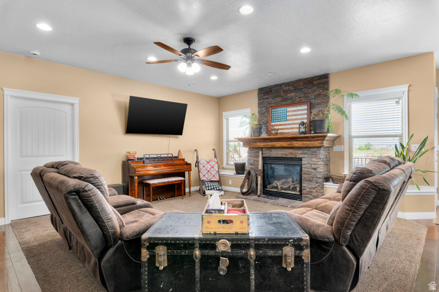 5702 950 North Ogden, UT 84404 - Photo 14 of 36 Living area featuring a stone-clad fireplace with a wood mantel, a ceiling fan with integrated lighting, recessed lighting, and wood-finish flooring