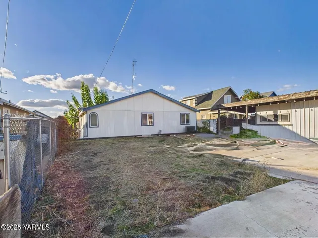 a view of a house with backyard and wooden fence