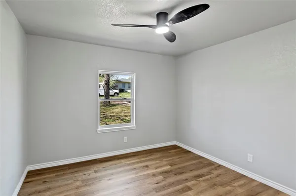 an empty room with windows and fan