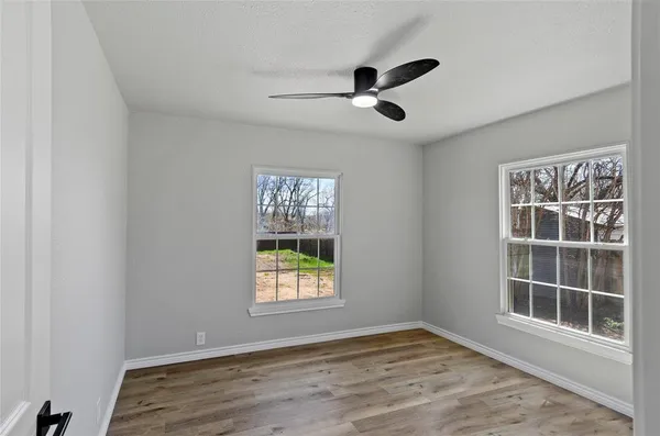 a view of an empty room with a window and wooden floor