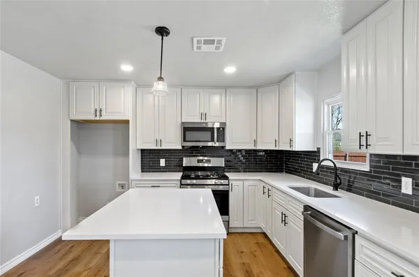 a kitchen with granite countertop a sink stainless steel appliances and white cabinets