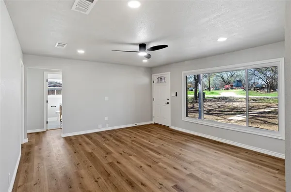 a view of an empty room with wooden floor and a window