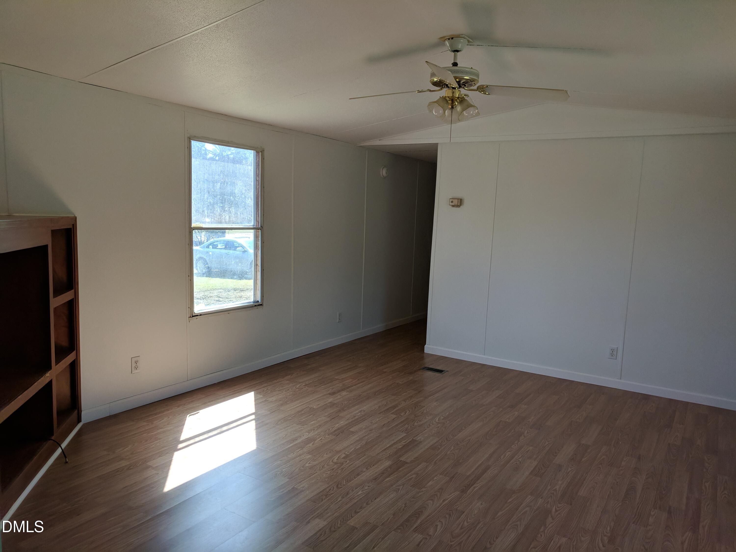 123 Ellington's Path Henderson, NC 27537 - Photo 2 of 4 an empty room with wooden floor fan and windows