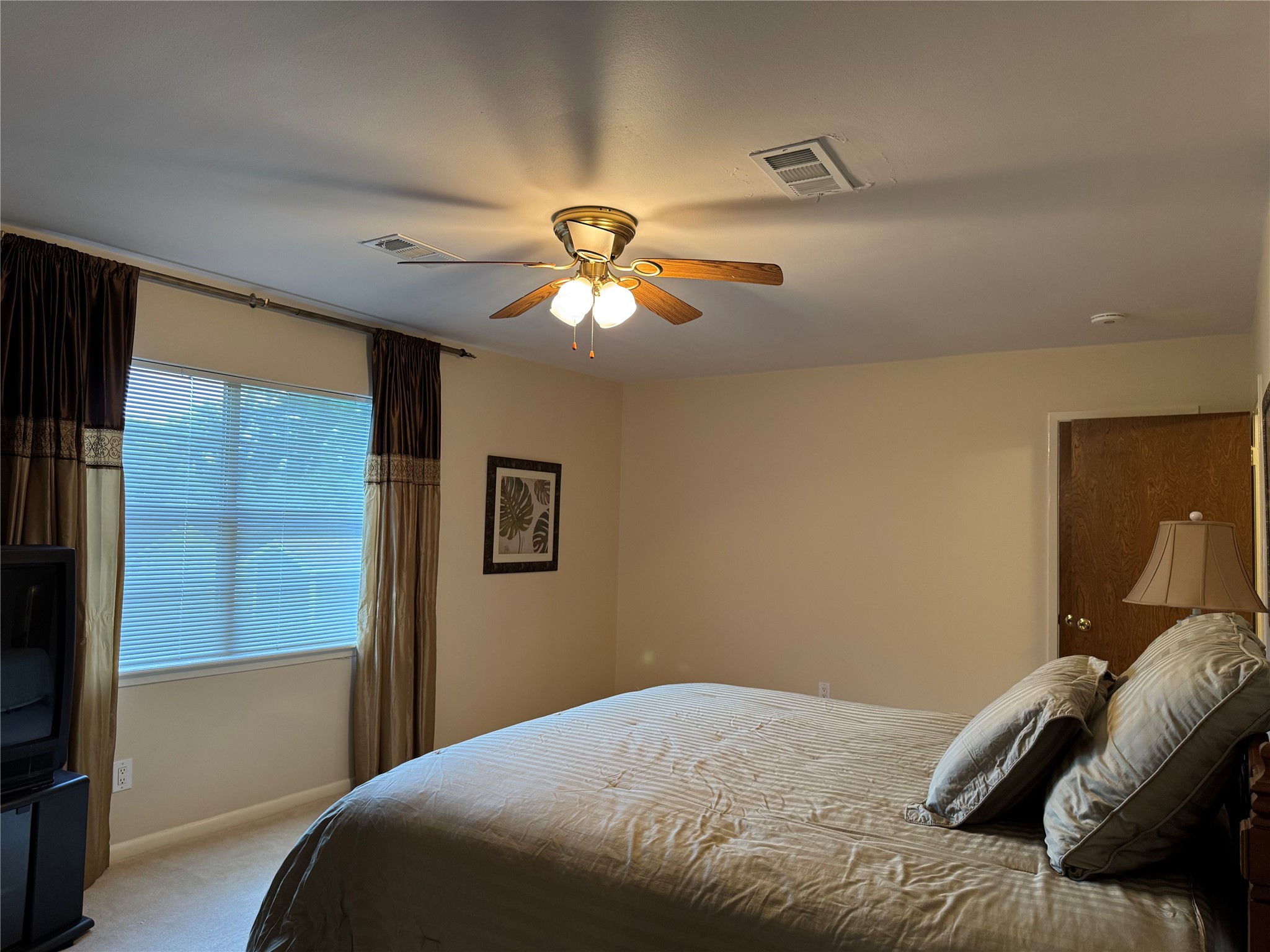203 East Thornton Road Houston, TX 77022 - Photo 13 of 18 Another view of the second-floor primary bedroom with a large window, elegant curtains, and neutral walls.