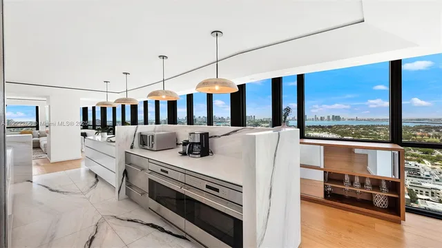 a large white kitchen with stainless steel appliances granite countertop a lot of counter space and a sink