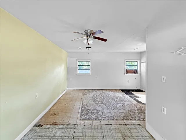 a view of a big room with windows and chandelier fan