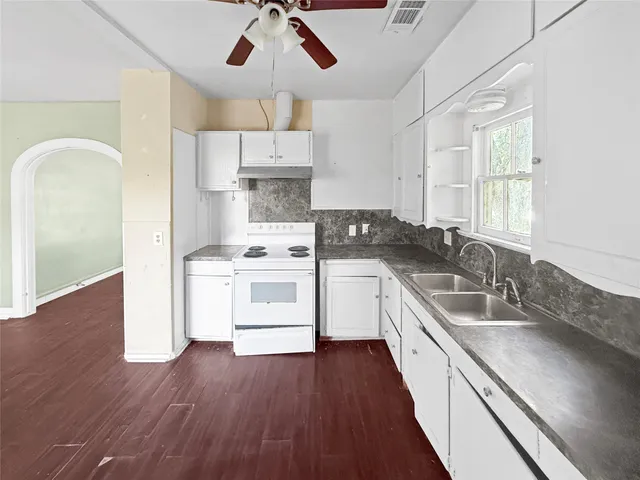 a kitchen with stainless steel appliances granite countertop a sink a stove and wooden floor