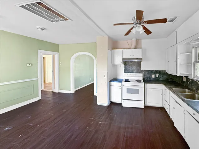 a kitchen with stainless steel appliances white cabinets and wooden floor