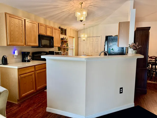a kitchen with stainless steel appliances granite countertop a refrigerator a stove top oven a sink dishwasher and wooden cabinets with wooden floor