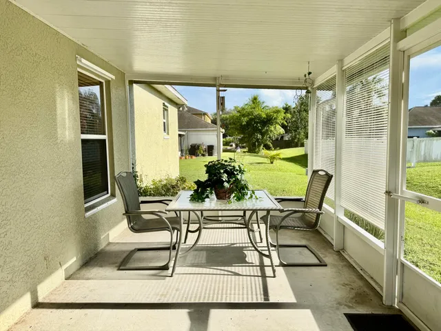 a view of a patio with table and chairs potted plants and floor to ceiling window