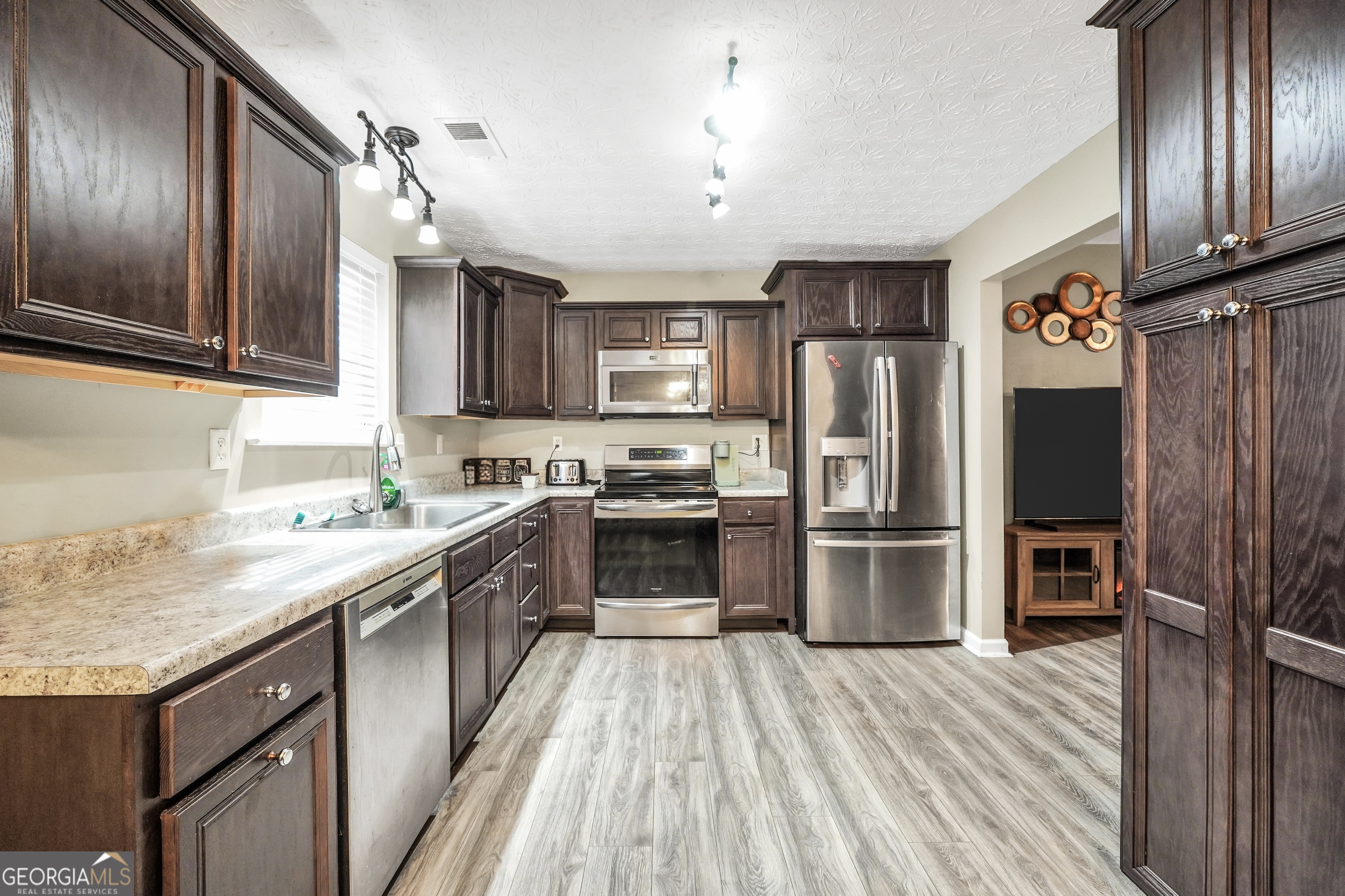 610 Kyle Court Locust Grove, GA 30248 - Photo 12 of 35 a large kitchen with a center island wooden floor stainless steel appliances and cabinets