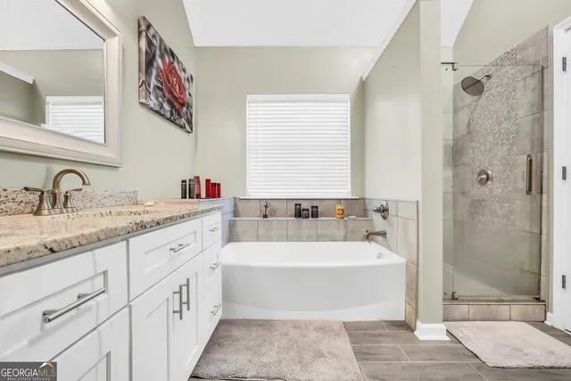 a bathroom with a tub sink shower and mirror