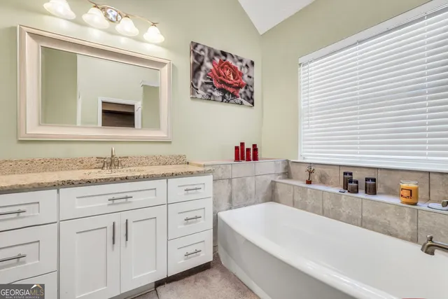 a bathroom with a tub sink and mirror