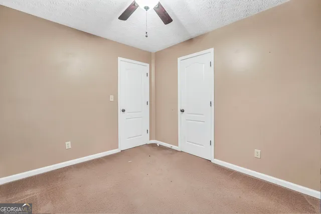 an empty room with a window and a ceiling fan