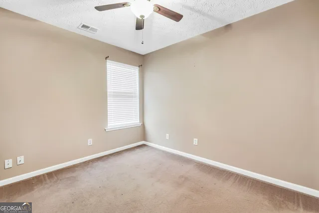 an empty room with a window and a ceiling fan